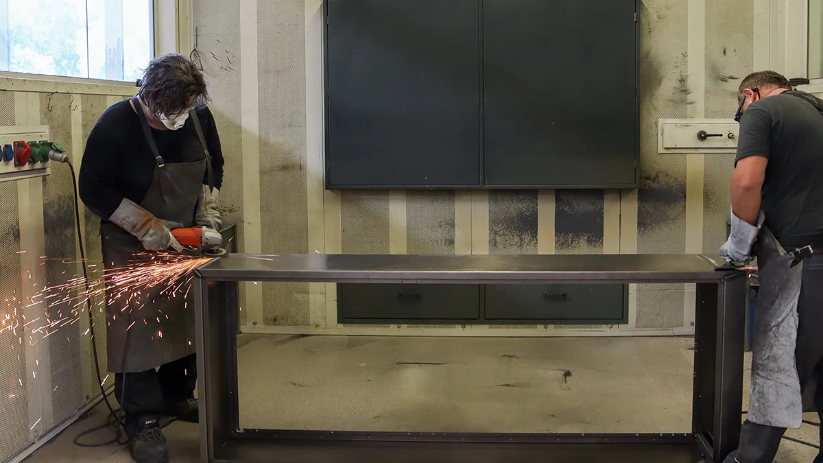 Männer schleifen Kanten von Schaltschrank ab